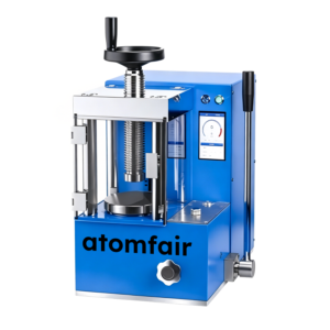ATOMFAIR® electric tablet press with a blue desktop chassis, top handwheel mechanism, clear enclosure door, and side control lever.