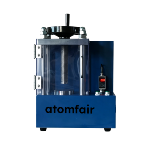 ATOMFAIR® electric tablet press featuring a blue desktop base, a clear enclosure chamber, and a vertical digital gauge display with control buttons.