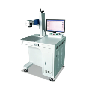 ATOMFAIR® fiber laser marking machine featuring a white workstation table with a side metal column laser arm, a desktop computer monitor, and a front key panel.