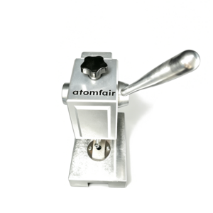 ATOMFAIR® manual coin cell disc cutting machine tool with a silver metallic block body, a top black knob, and a long steel handle.