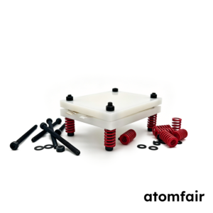 ATOMFAIR® off-white PP plastic pouch cell test fixture surrounded by scattered black screws and red springs on a white background.