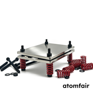 ATOMFAIR® silver stainless steel pouch cell test fixture surrounded by scattered black screws and red springs on a white background.