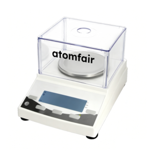 ATOMFAIR® YP602N white electronic balance with a square transparent plastic draft shield and circular pan on a white background.